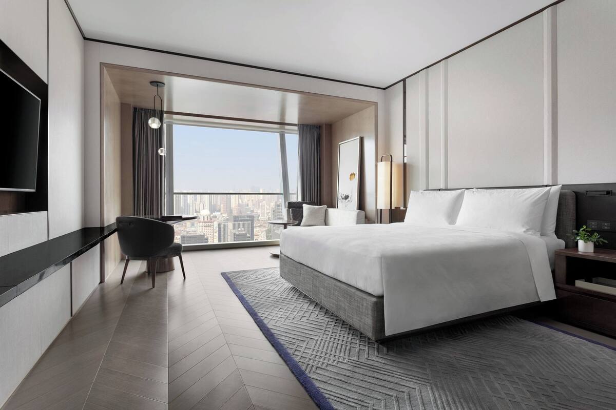 Une chambre d’hôtel moderne avec un grand lit, un bureau et une vue sur la ville.