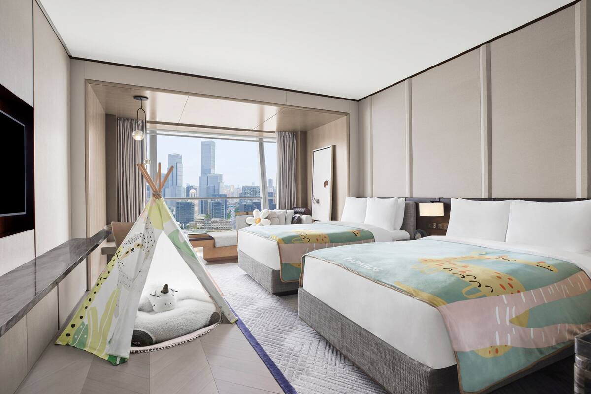 Une chambre d’hôtel avec deux lits, une vue sur la ville, une tente et un téléviseur.