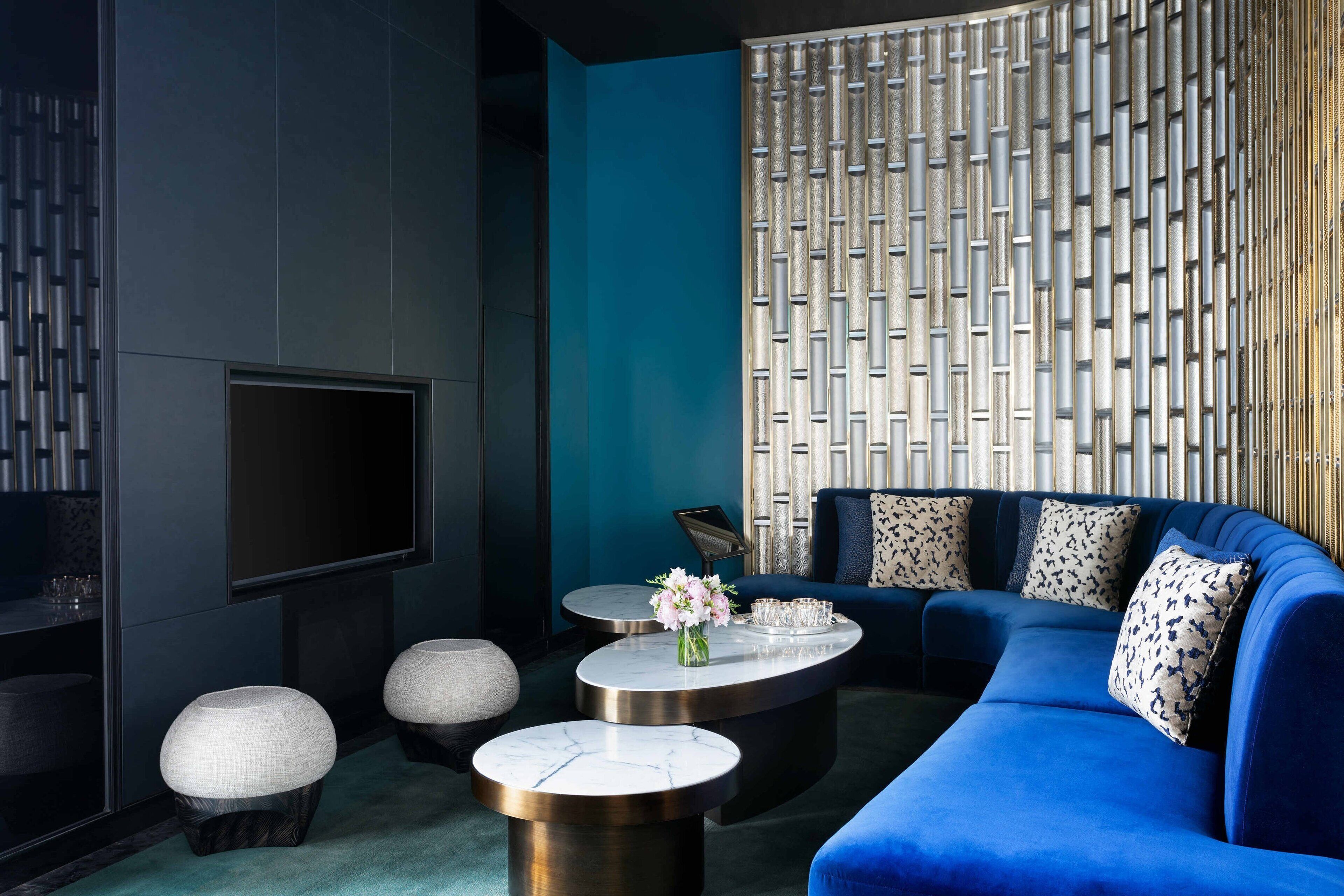 A modern living room with a blue sofa, round coffee tables, and a TV mounted on the wall.