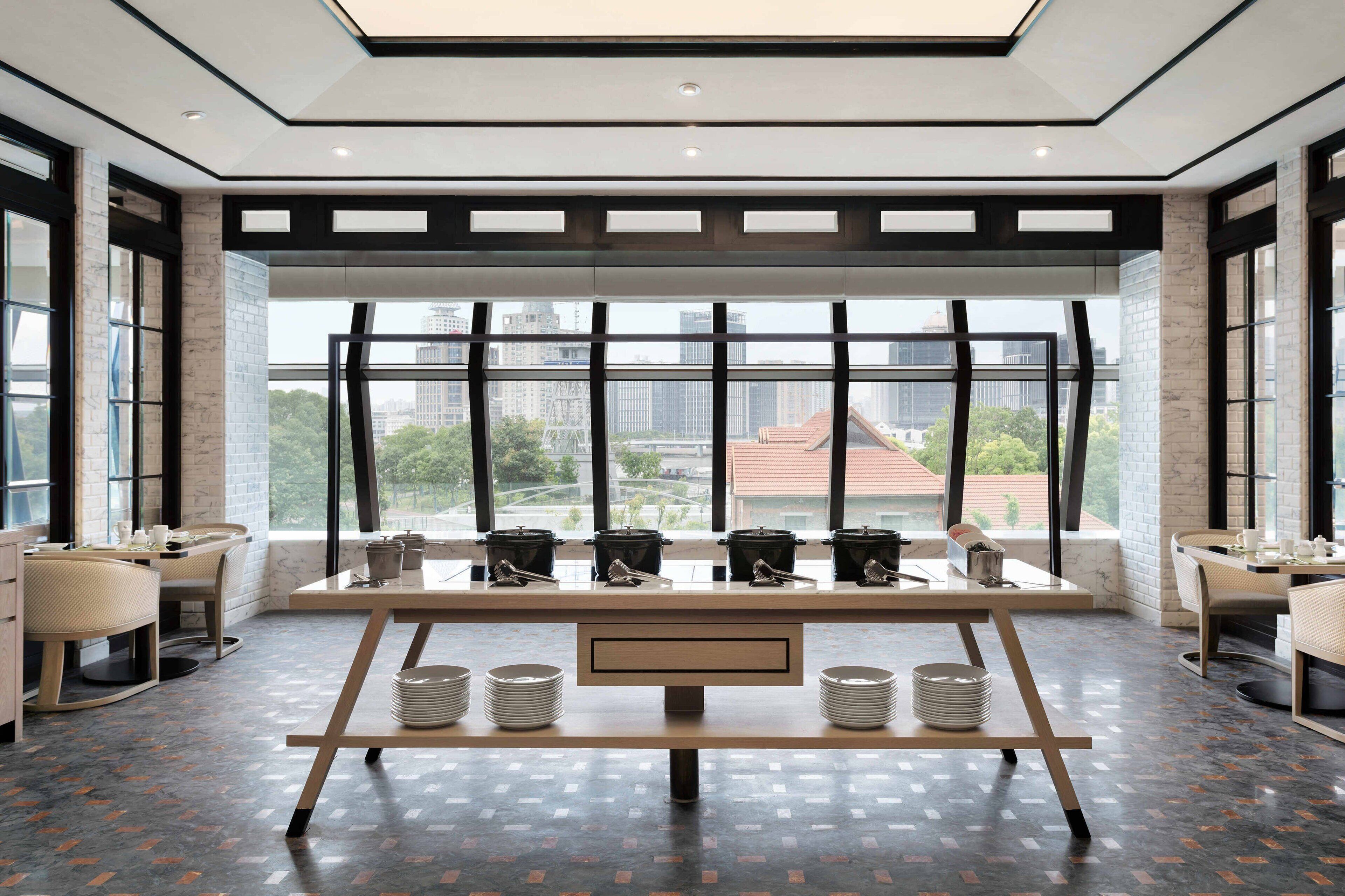 Un comedor moderno con una mesa larga, múltiples sillas y vistas de la ciudad a través de amplios ventanales.