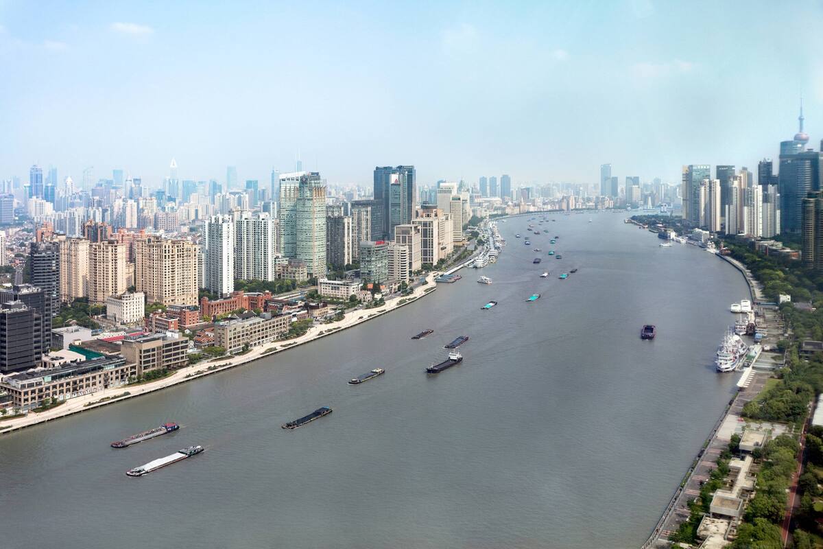 Une rivière où naviguent de nombreux bateaux, et un paysage urbain avec des immeubles de grande hauteur de part et d’autre.