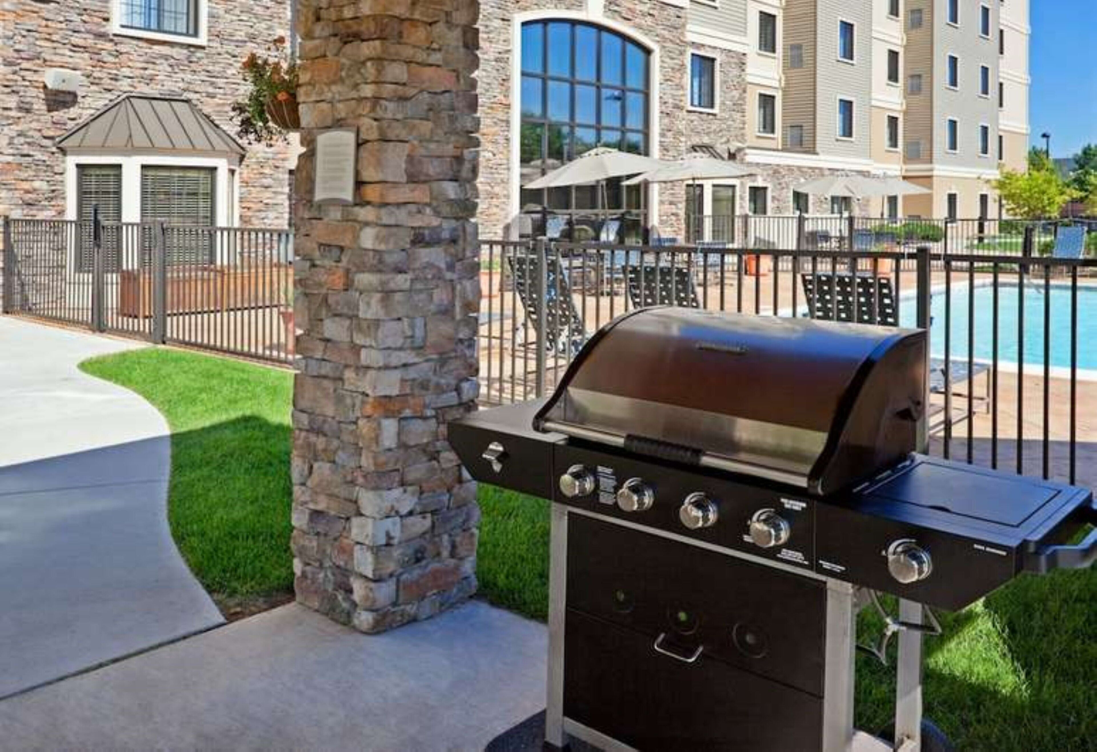 Un pilier de pierre, un barbecue et une piscine.