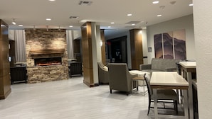 A modern living room with a stone fireplace, comfortable seating, and a dining area.