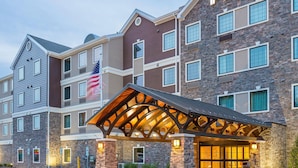 A multi-story hotel with a stone facade, a large American flag, and a covered entrance.