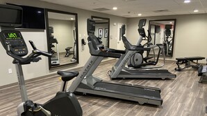 A gym with treadmills, exercise bikes, and a digital display.