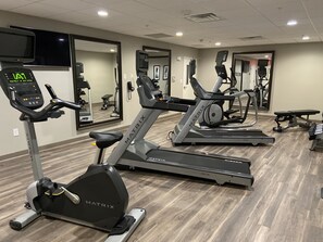 A gym with treadmills, exercise bikes, and a digital display.