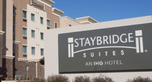 A Staybridge Suites sign with a modern building in the background. - Staybridge Suites Denton by IHG (Denton)