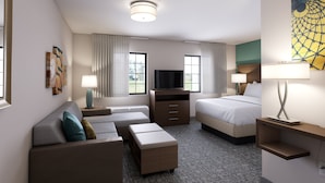 A hotel room with a sofa, a bed, a TV, a desk, and a lamp.