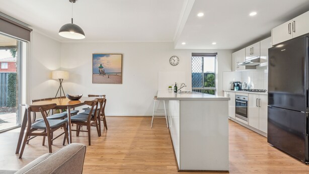 Una cocina moderna con una isla central, una mesa de comedor de madera y sillas.