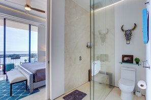 A modern bathroom with a glass shower enclosure, a toilet, and a decorative bull head on the wall.