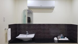 A bathroom with a black marble wall, a white sink, a mirror, and a Samsung air conditioner. - Cess Summer Boutique Hotel (Kalibo)
