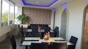 A dining area with a table set for six, a plant, and a patterned wall. - Cess Summer Boutique Hotel (Kalibo)
