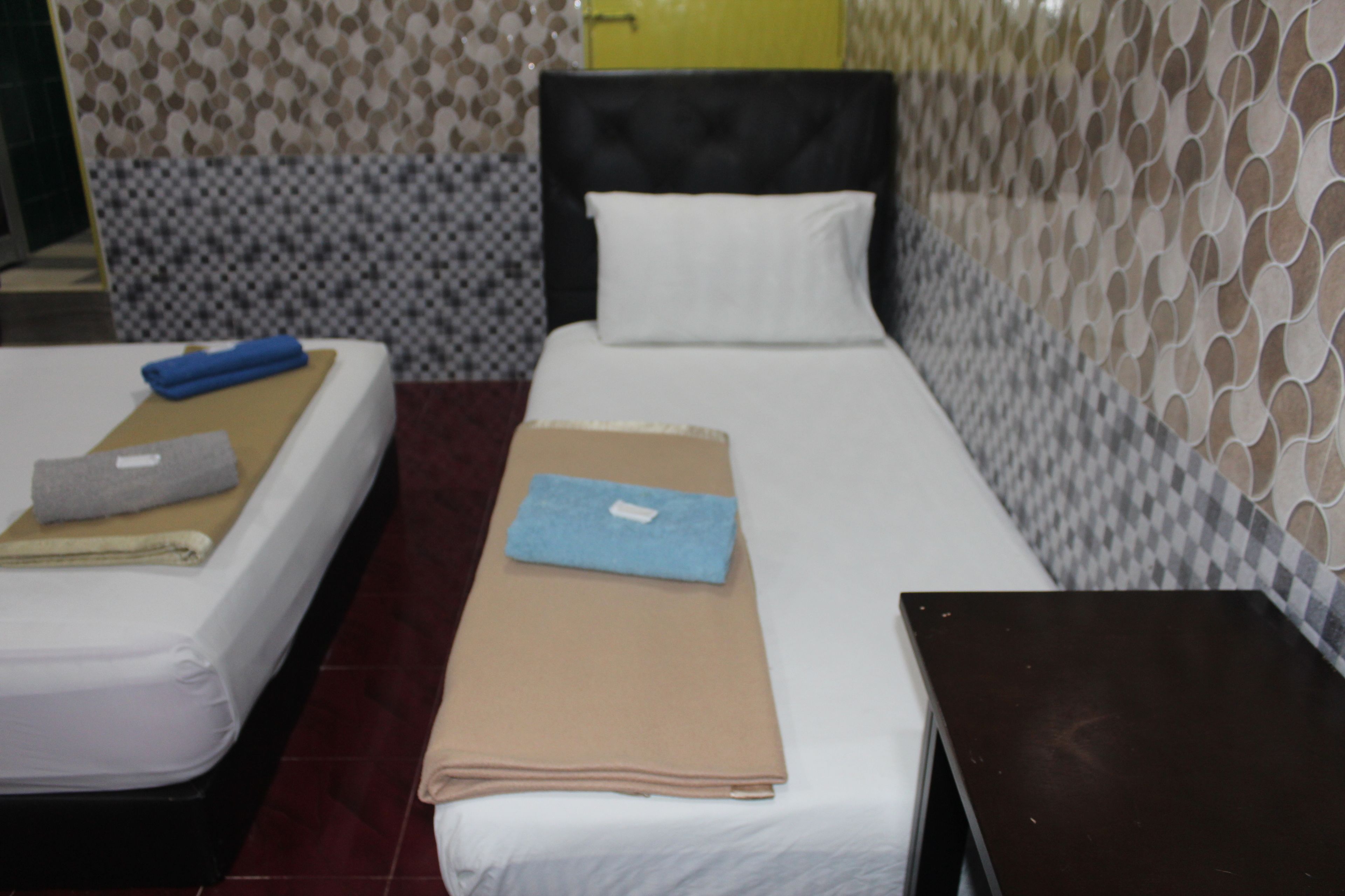 Una cama individual con cabecera, una mesita de noche y una pared con diseño decorativo.