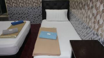 Una cama individual con cabecera, una mesita de noche y una pared con diseño decorativo.
