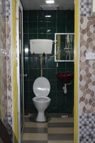 A bathroom with a toilet, a red sink, and a green tiled wall.