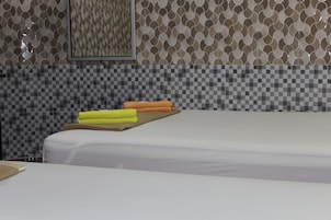 A hotel room with a checkered tile backsplash, a bed with white bedding, and two rolled towels on the bed.