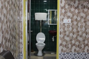 A bathroom with a toilet, a red sink, and a water heater.
