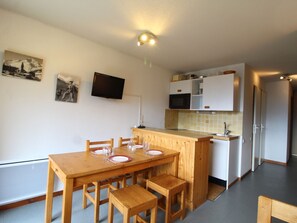 A compact kitchen with a wooden table and chairs, a microwave, and a small cabinet. - Cozy Apartment for 4 in Val Cenis Le Haut, Near Slopes and Amenities (Lanslevillard)