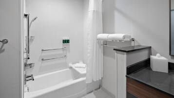 A modern bathroom with a bathtub, shower, and a vanity with a mirror.