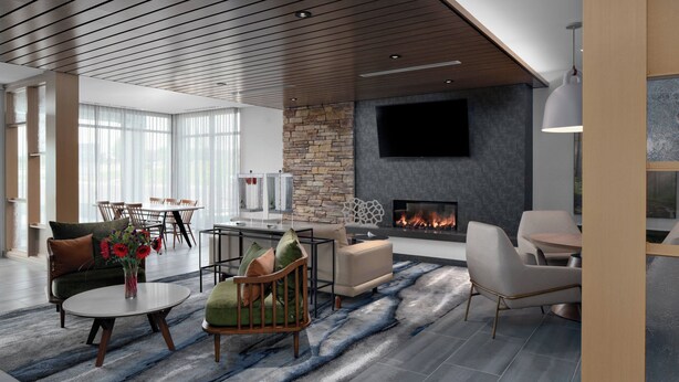 A modern living room with a fireplace, a dining area, and a seating area with a view of the outdoors.