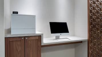 Un espacio de oficina moderno con un escritorio blanco, un iMac de Apple y una impresora blanca.
