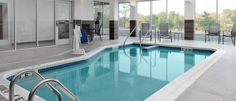 An indoor swimming pool with clear water, a 4'6" depth marking, and a view of the outdoors through large windows.