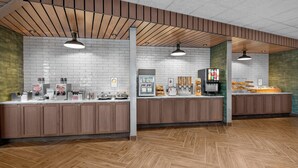 A modern kitchen area with wooden cabinets, white tiled walls, and a herringbone wood floor.