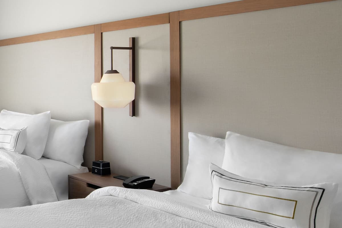 A hotel room with a bed, bedside tables, a lamp, and a phone.