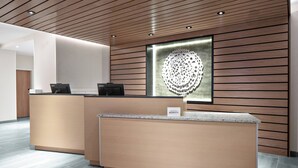 A modern reception desk with a wooden panel wall and a glass art piece.
