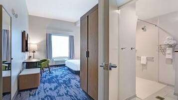 Une chambre d’hôtel avec un lit, un bureau et une chaise, une douche et une grande fenêtre.