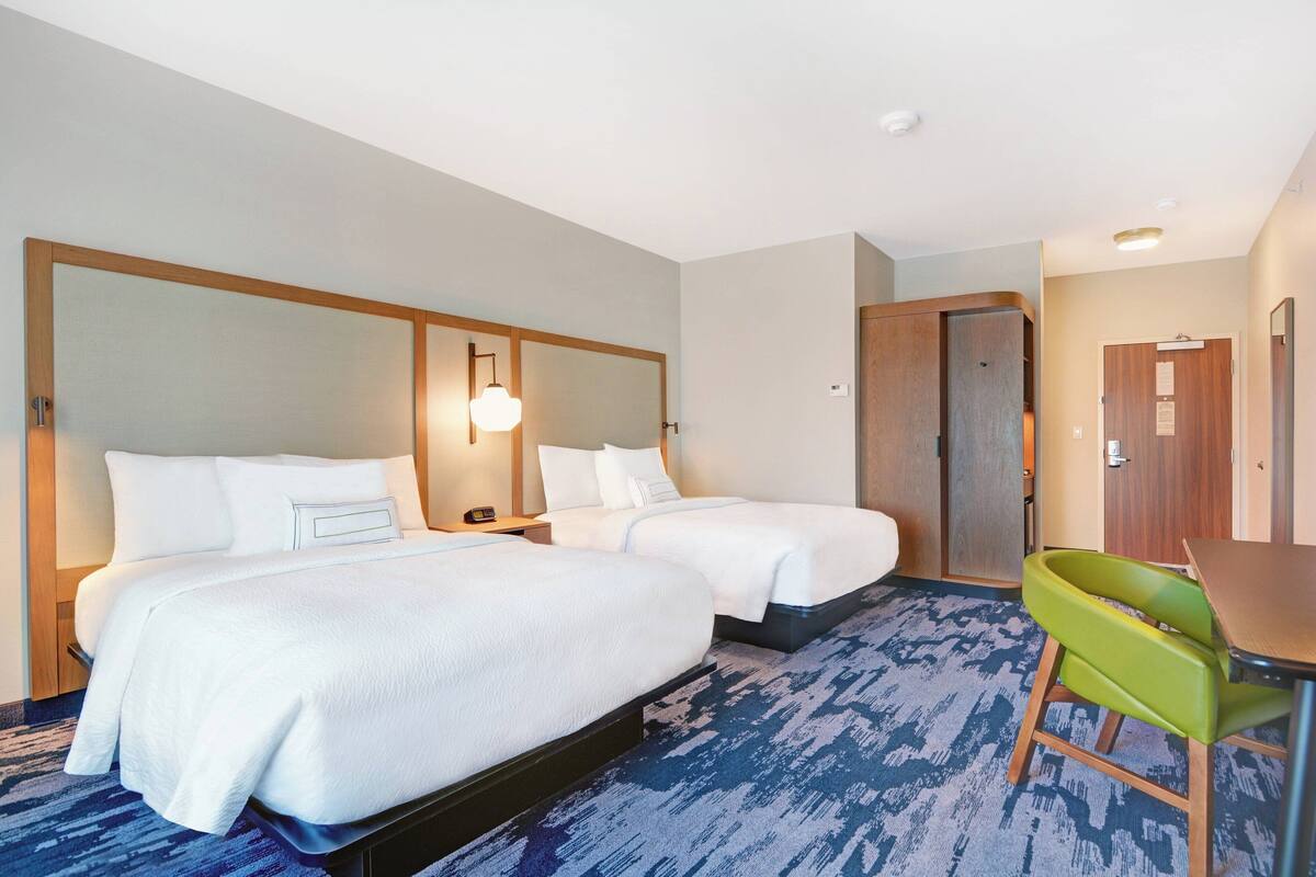 Une chambre d’hôtel avec deux lits, un bureau et une chaise.
