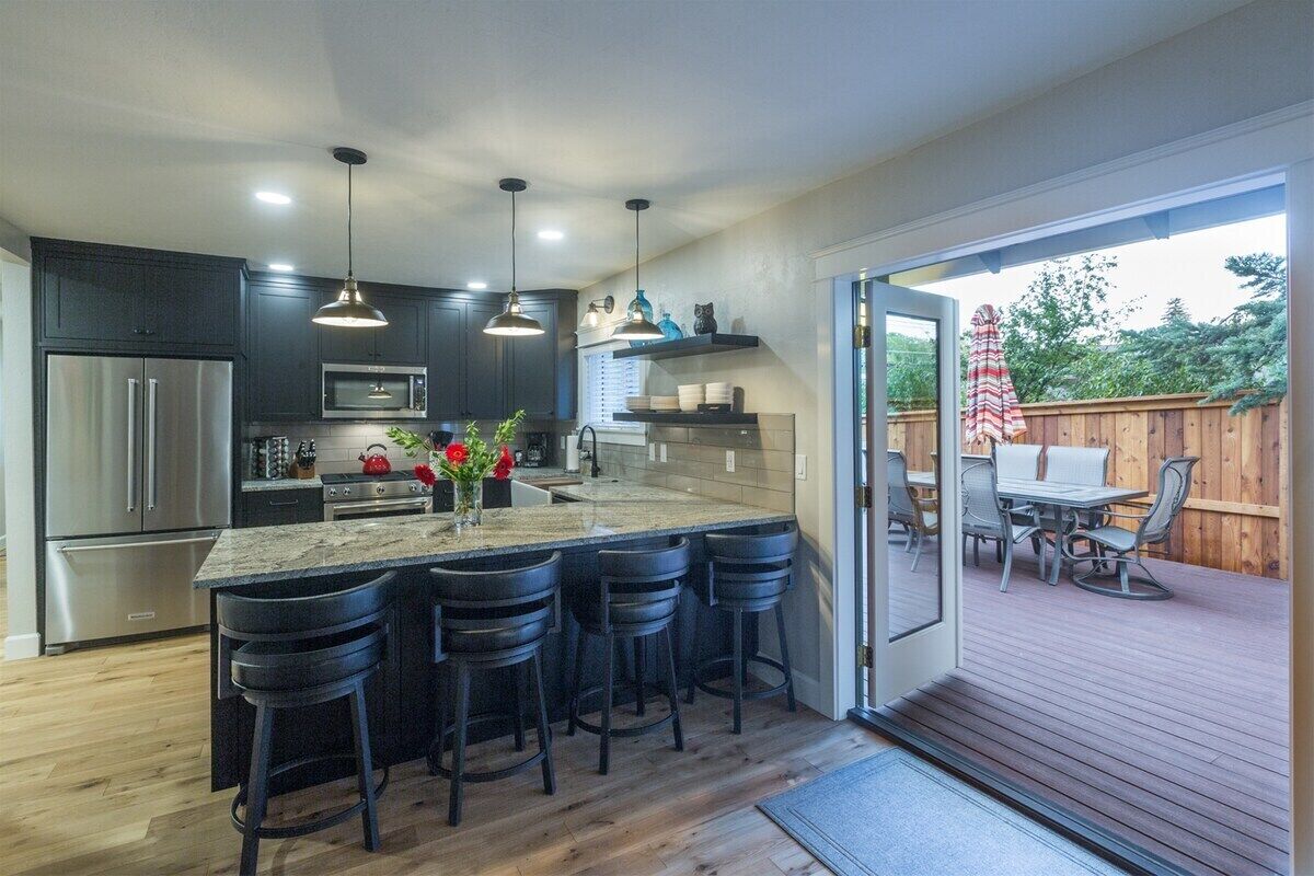 A modern kitchen with dark cabinetry, stainless steel appliances, and a central island with bar stools.