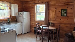 A cabin interior with a kitchen, dining area, and a sign on the wall.