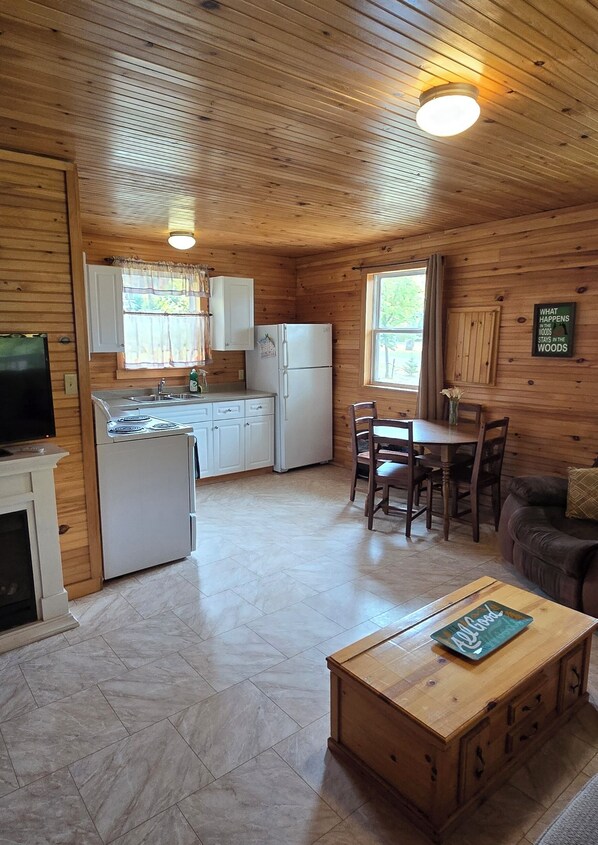 A wooden cabin interior with a kitchen, dining area, and living room.