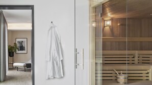Une salle de spa moderne avec une paroi en verre, des bancs en bois et un sauna.