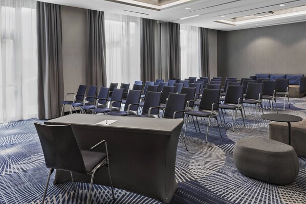 A conference room with rows of chairs, a table, and a carpeted floor.