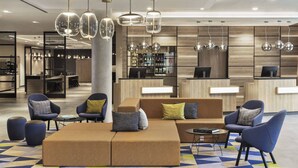 Un hall d’entrée moderne avec des espaces de détente, un comptoir d’accueil et un bar.