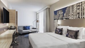 Une chambre d’hôtel moderne équipée d’un grand lit, d’un canapé, d’un bureau et d’un téléviseur à écran plat.
