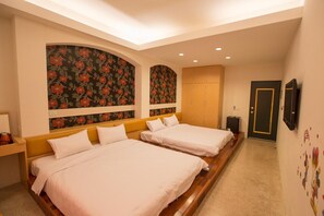 A hotel room with two beds, a wooden headboard, a large floral-patterned wall, a wardrobe, and a door with a mirror. - Lukang Art Garden Inn (Lukang)