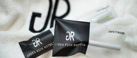 Una toalla blanca con el logotipo "DR GREEN RICH HOTELS" y un tubo de pasta dental "SAFETYRAZOR".