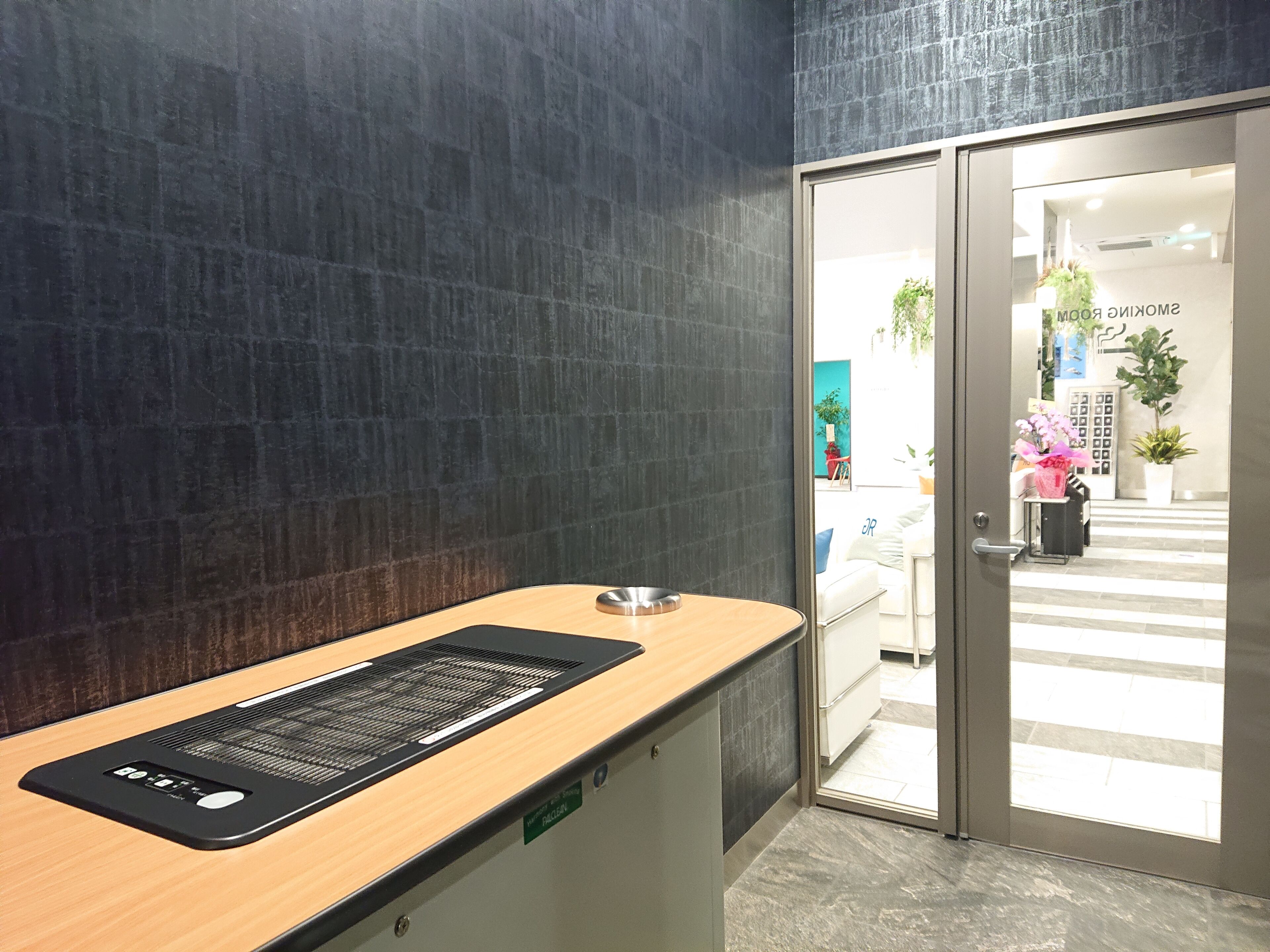 A reception desk with a digital screen, a metal bowl, and a sign indicating the room number.