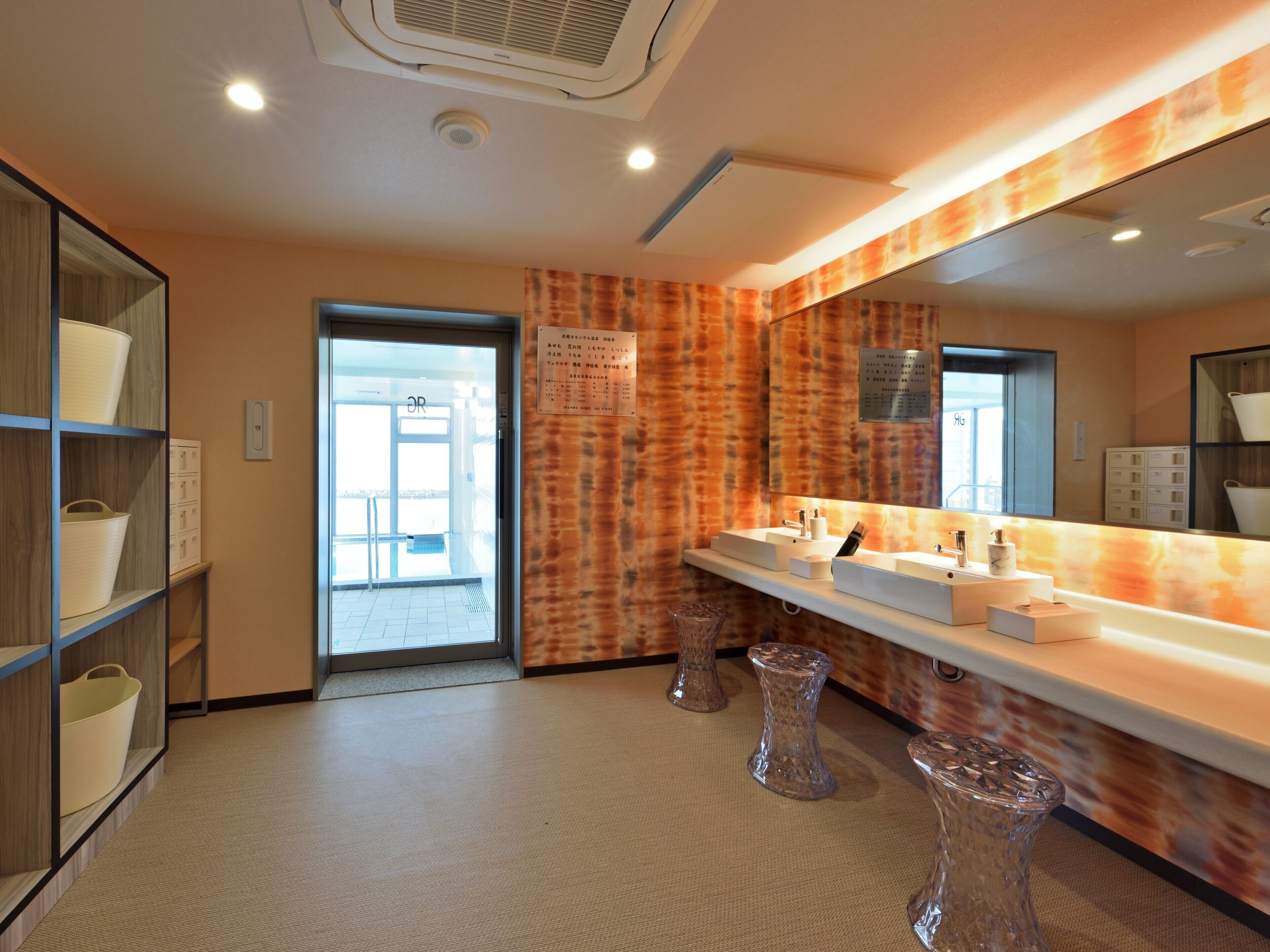 A modern bathroom with two sinks, a large mirror, and a wooden shelf with baskets.