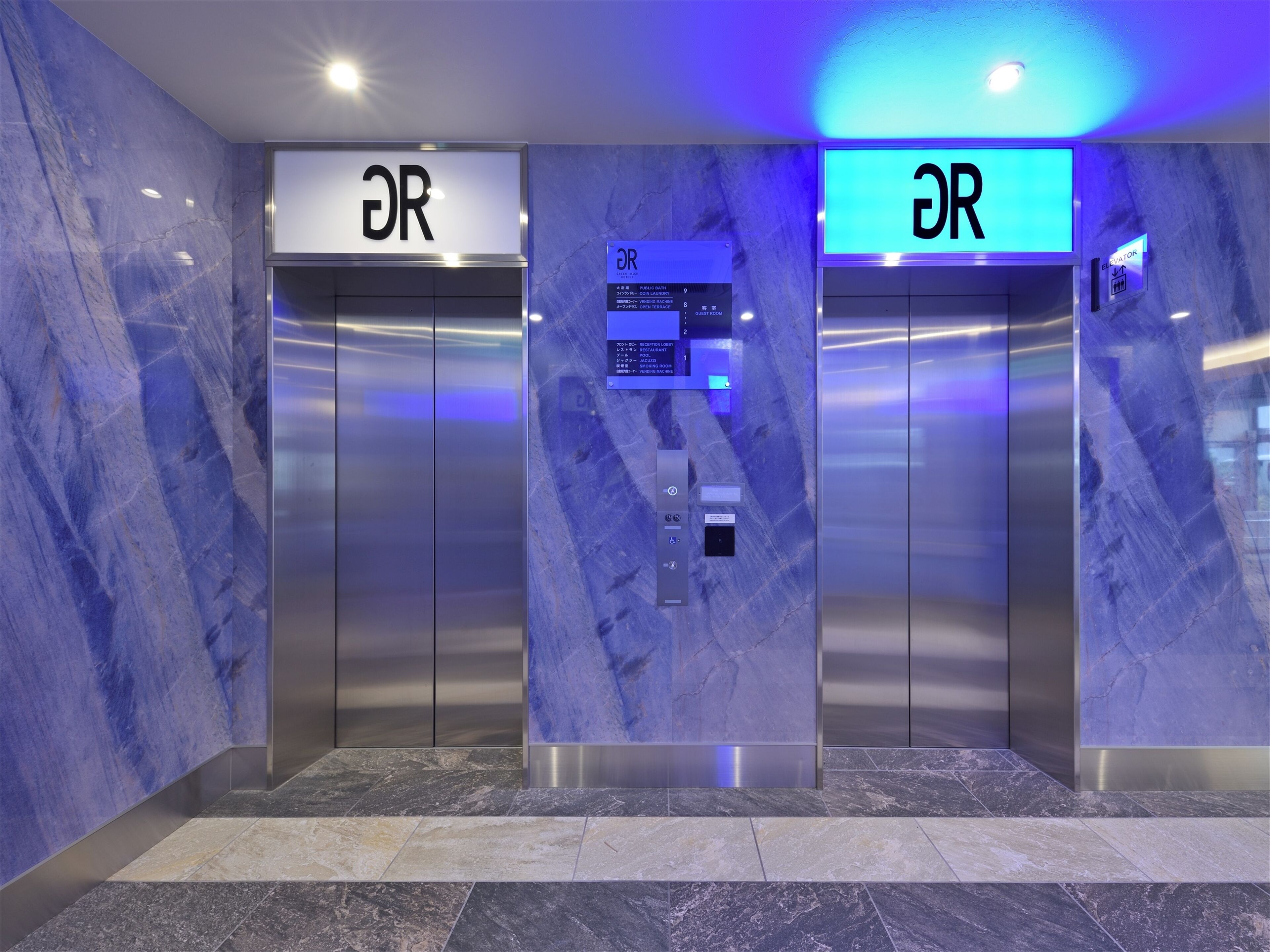 Two elevators with digital displays and a marble wall.