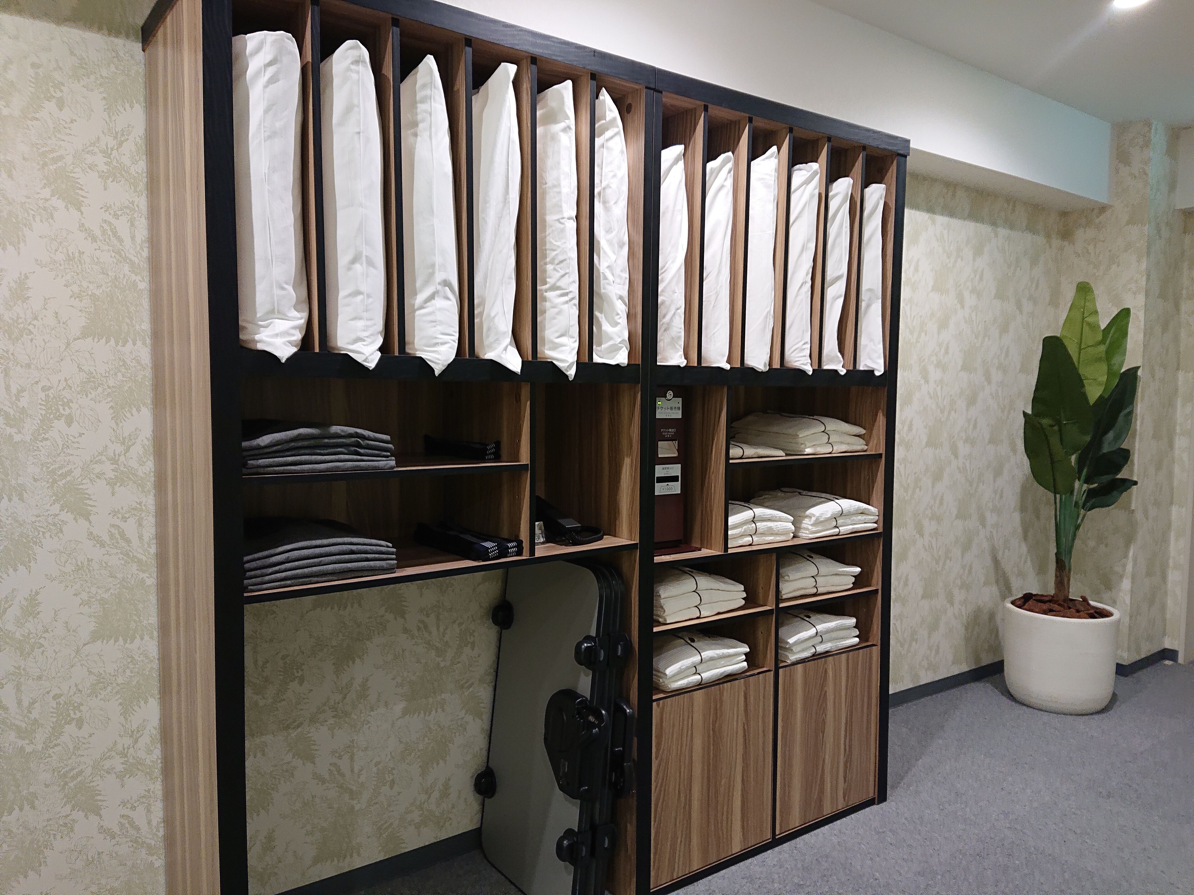A storage unit with multiple shelves, some holding folded white linens and others with folded towels.