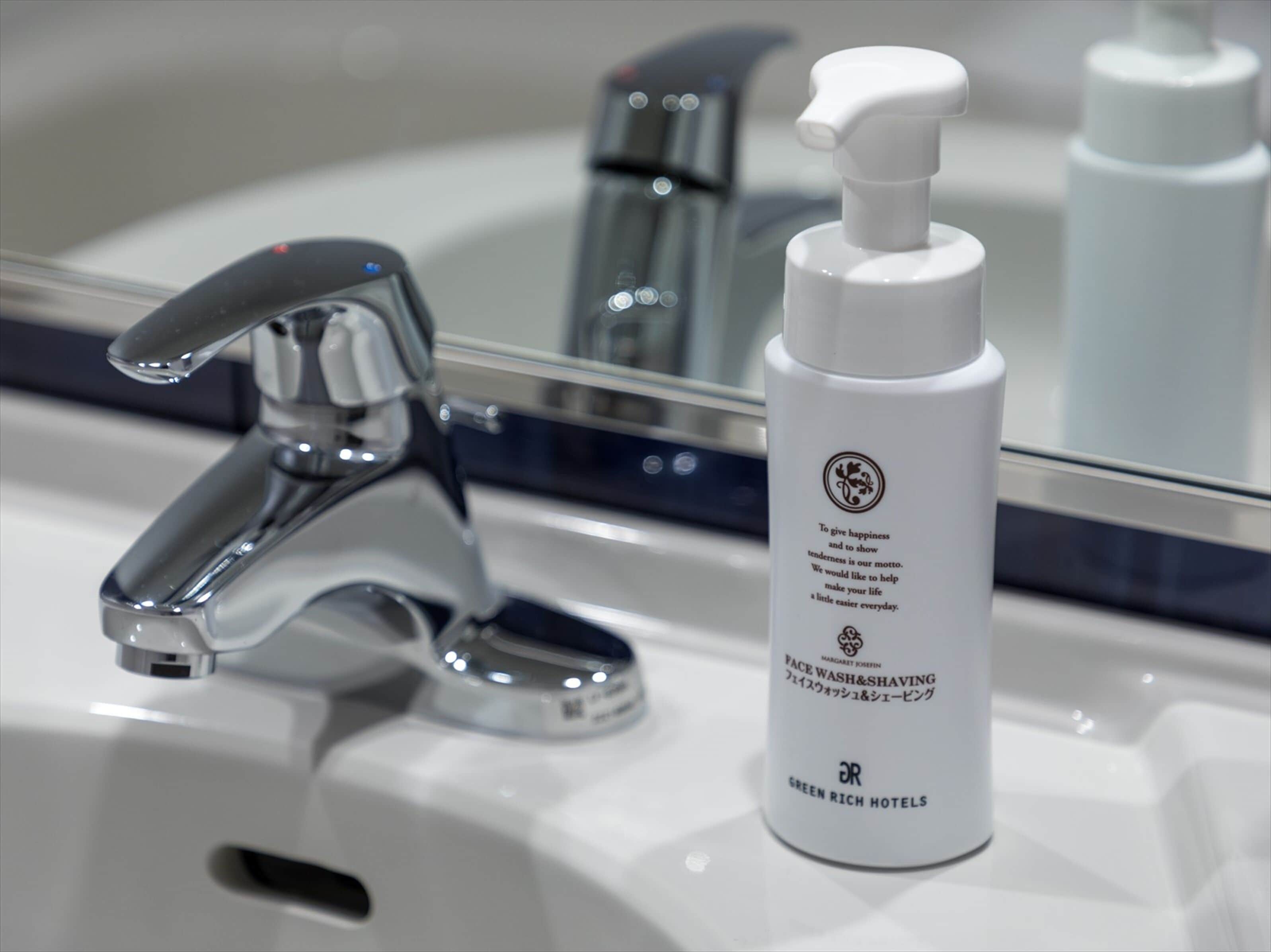 A bathroom sink with a chrome faucet and a white bottle of face wash.