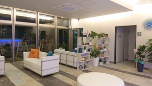 Een moderne lobby met een witte bank, een ronde witte tafel en een plantenunit.