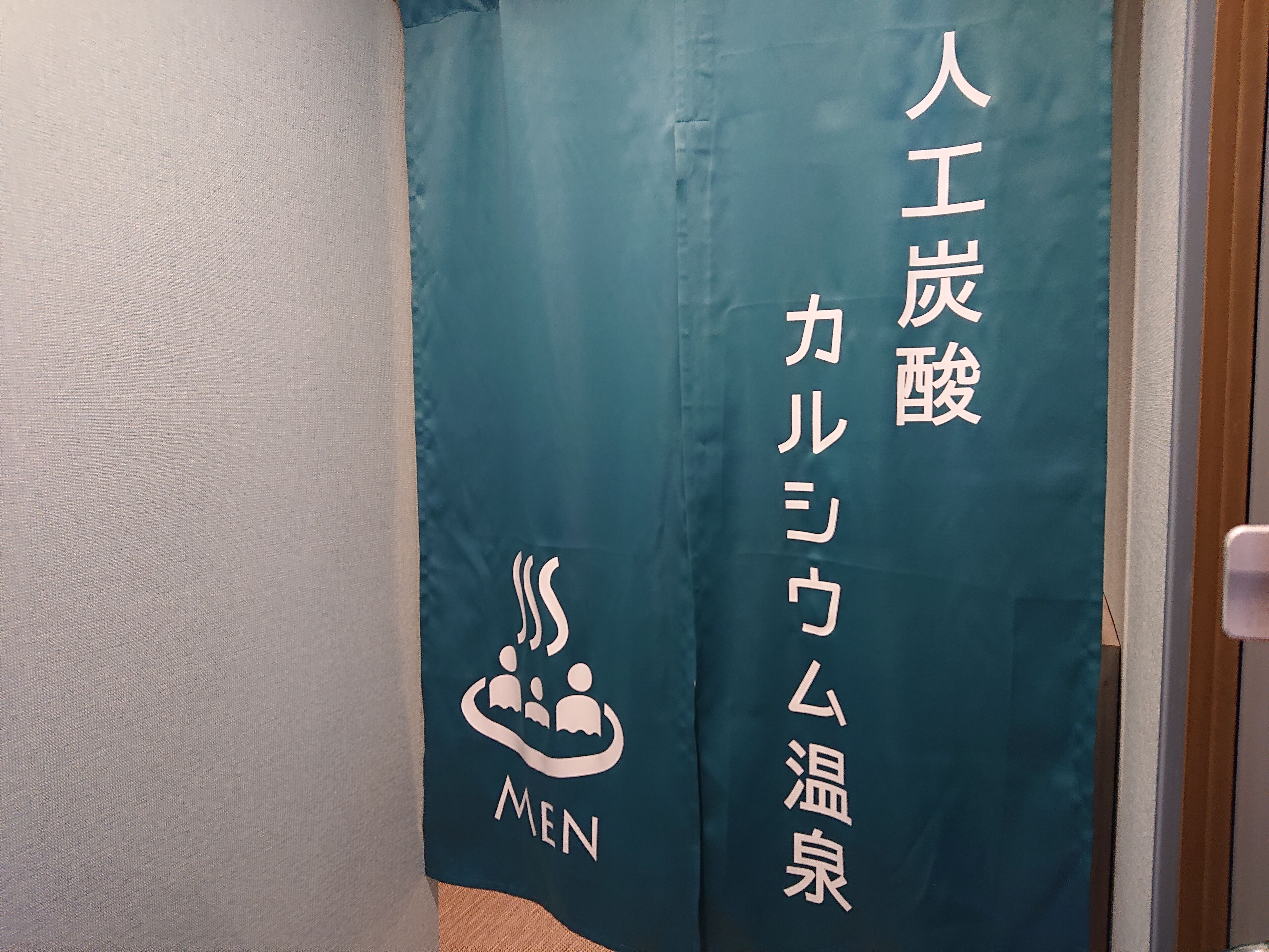 A teal curtain with Japanese text and a logo featuring three figures and the word "MEN".