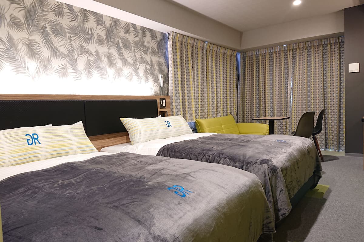 Une chambre d’hôtel avec deux lits, une petite table et une chaise.