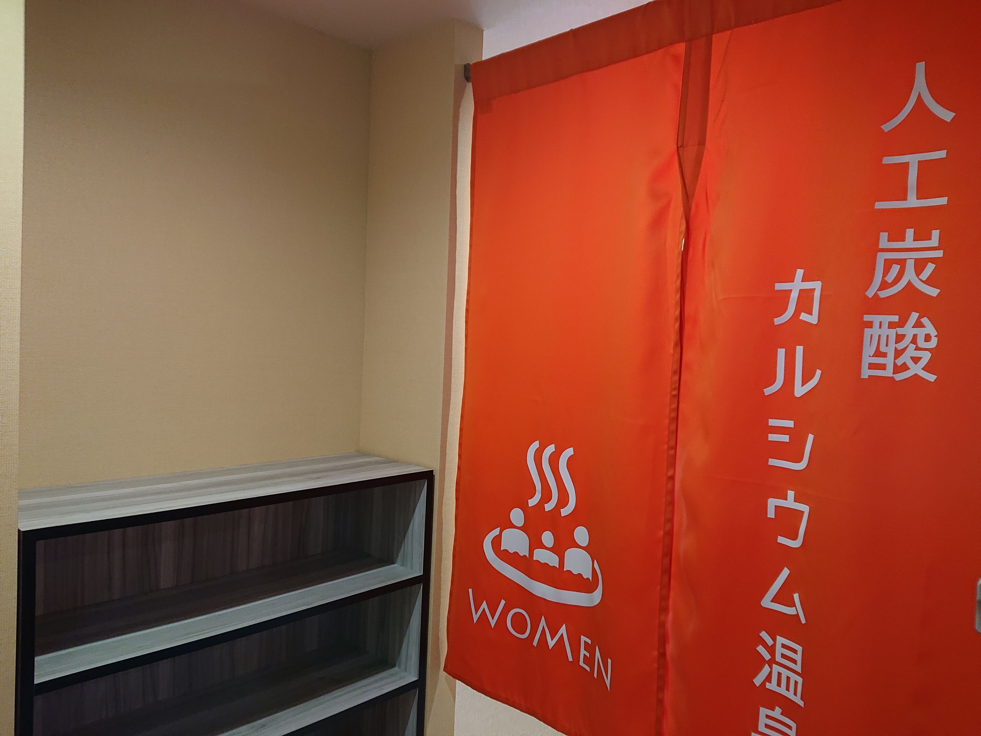 A room with a red banner featuring Japanese text and a logo with three figures and the word "WOMEN".