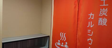 Een kamer met een rode banner met Japanse tekst en een logo met drie figuren en het woord 'WOMEN'.